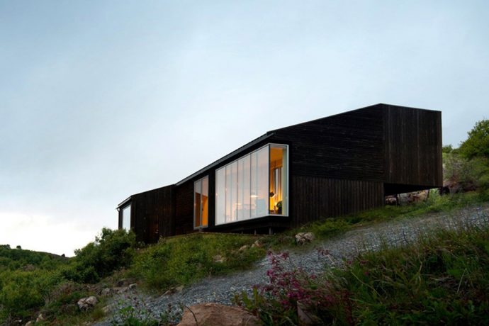 Experience the Norwegian sloped hills in this minimal blackwood cabin!