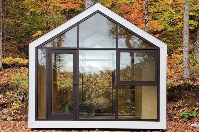 This tiny cabin shaped like the home icon features floor-to-ceiling facades for nature lovers!