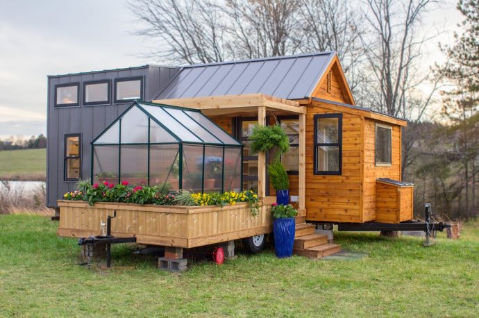 This tiny home inspired by Scandinavian design comes with a small greenhouse and a porch swing!