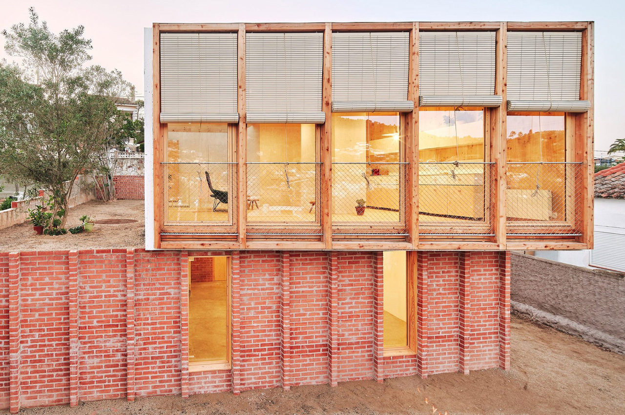 This prefabricated timber home in Barcelona has a bright red-brick building for a base