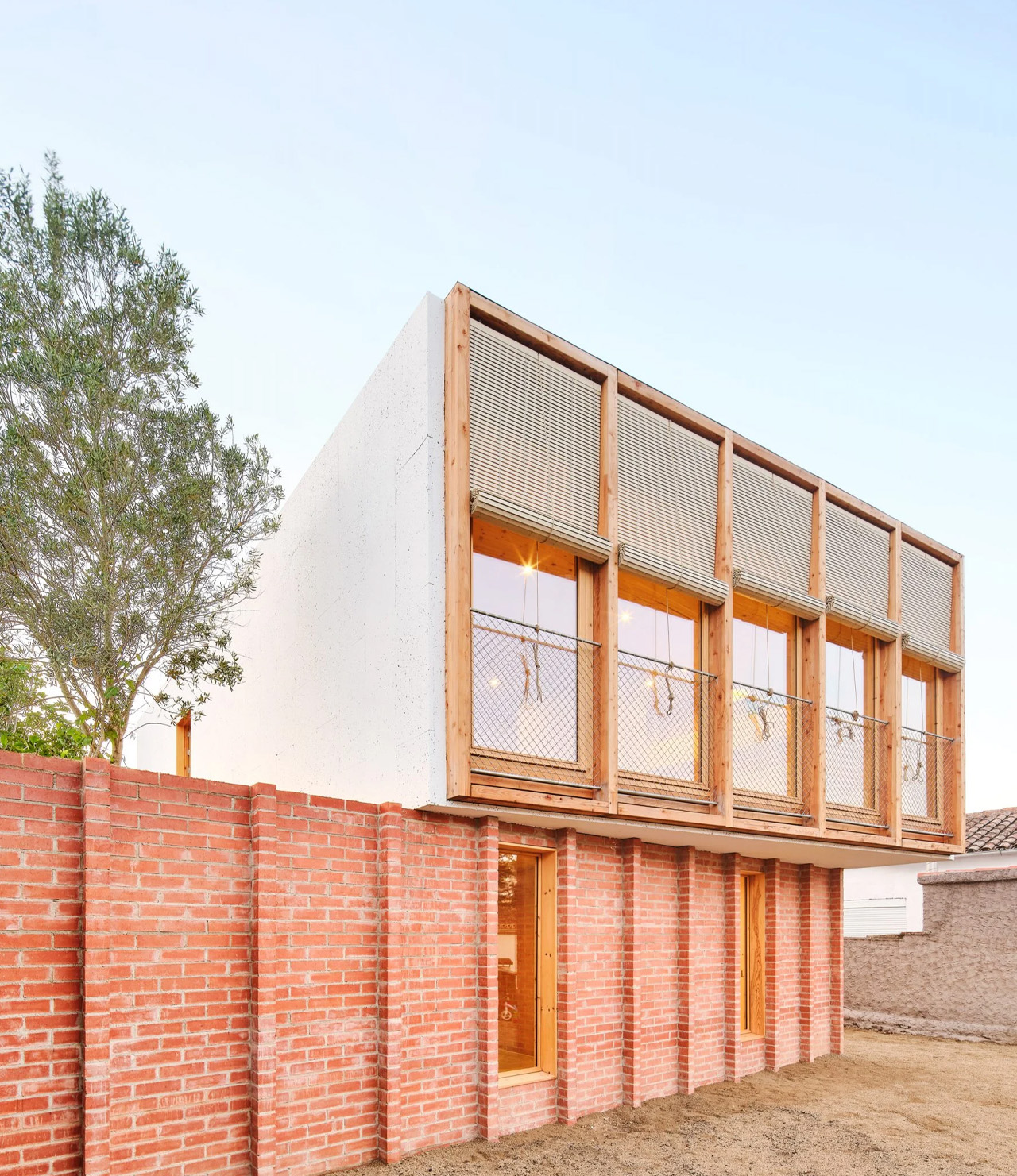 This prefabricated timber home in Barcelona has a bright red-brick building for a base