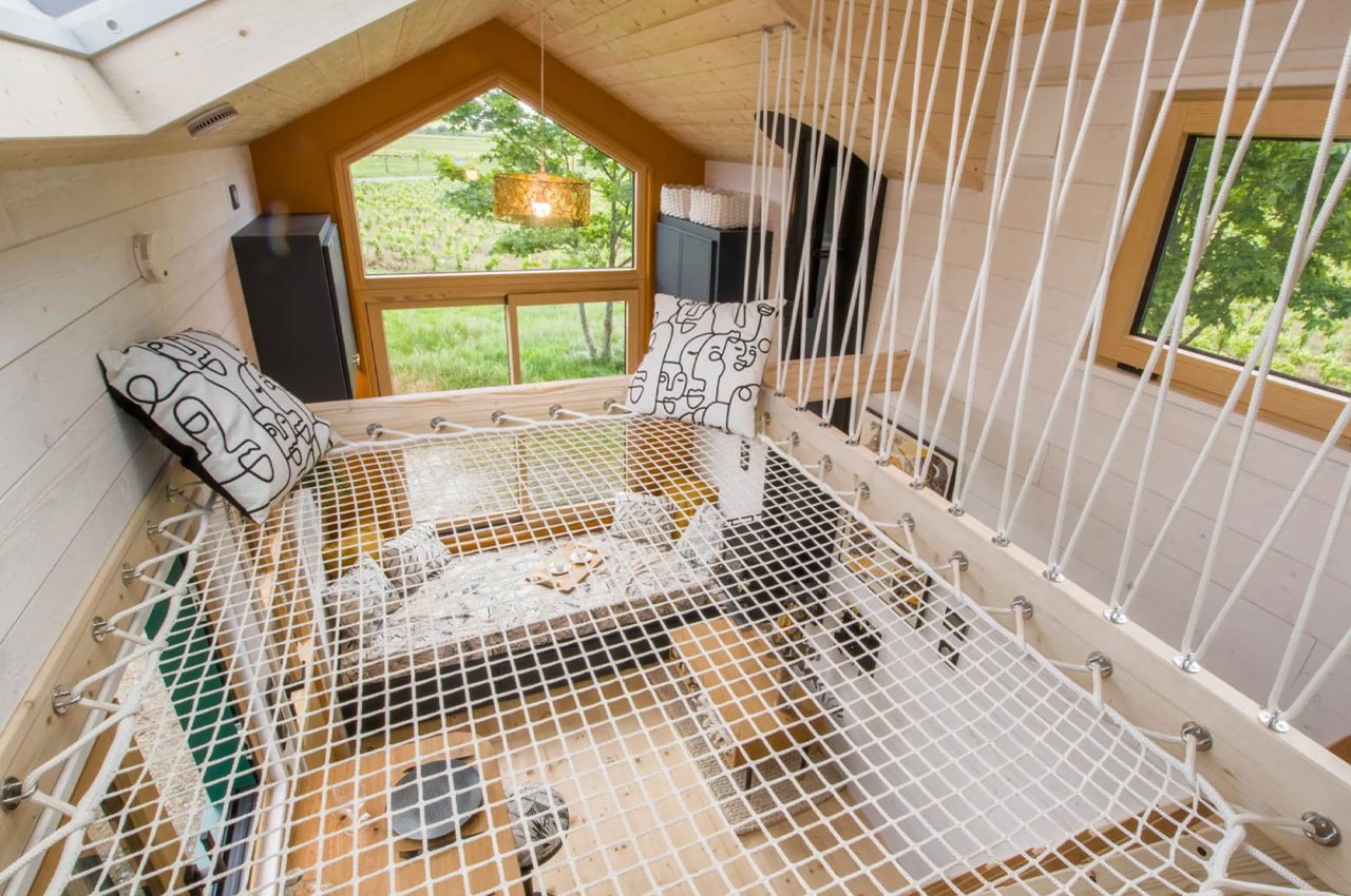 #French Tiny Home Has A Netted Loft Area Under A Skylight That Functions As A Cozy Reading Nook