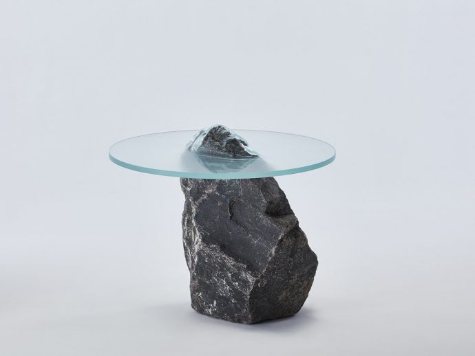 Glass and rock table look like a sharp stone is piercing through the surface