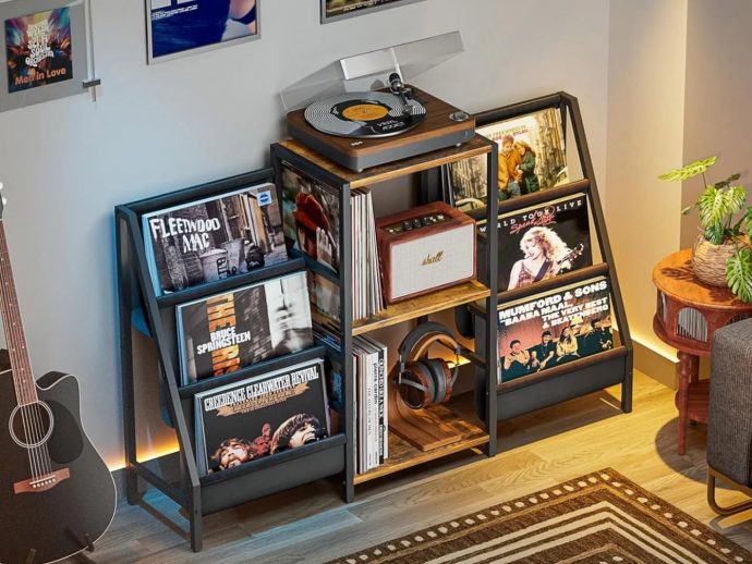 Home music corner with a turntable on top of a wooden rack and shelves full of vinyl records in a cozy room.