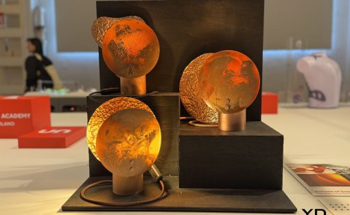 Copper-toned sculpture with four hammered circular disks mounted on copper posts on a black multi-level pedestal.