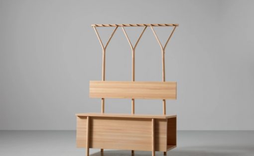 Wooden hall tree with three Y-shaped coat hooks above a bench and storage cabinet at the base, all in light oak finish