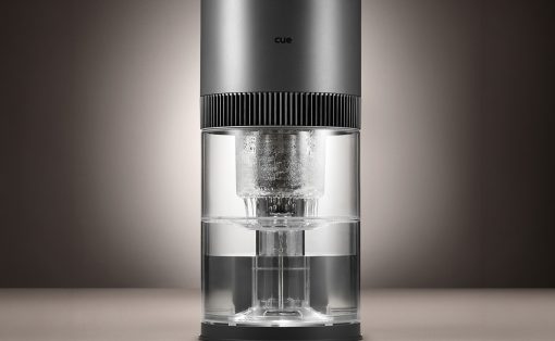 Sleek cylindrical coffee maker with a metallic top, ribbed band, and transparent glass water chamber.