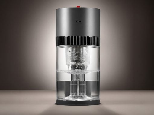Sleek cylindrical coffee maker with a metallic top, ribbed band, and transparent glass water chamber.