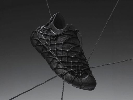 Black athletic shoe with a webbed, net-like lacing system suspended by cords on a gradient background