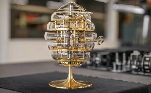Ornate brass-and-glass egg-shaped timepiece on a gold stand, displayed on a dark table cloth.