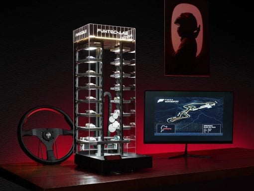 Glass multi-level car display case filled with miniature race cars, with a red-lit racing wheel and a monitor showing a Forza Motorsport race map.