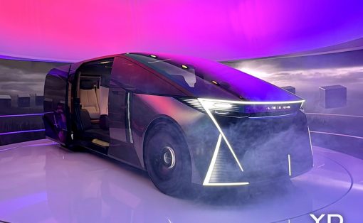 Futuristic concept minivan on a circular display platform with pink-purple lighting and smoke, angular LED front, YD Yanko Design watermark.