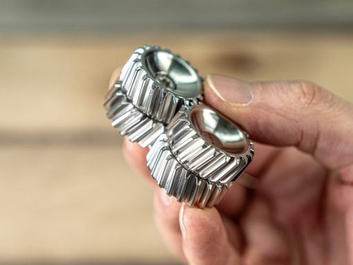 Close-up of a person's fingers holding two silver metal watch bands with interlocking links.