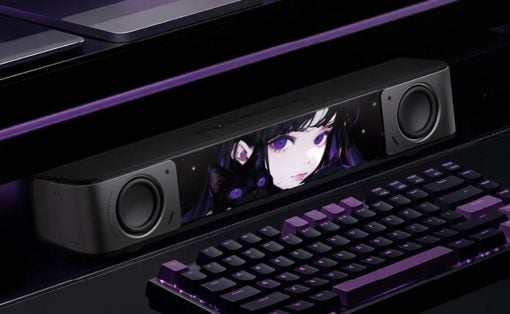 Gaming setup with a black soundbar showing anime artwork, flanked by two speakers and a purple-backlit keyboard.