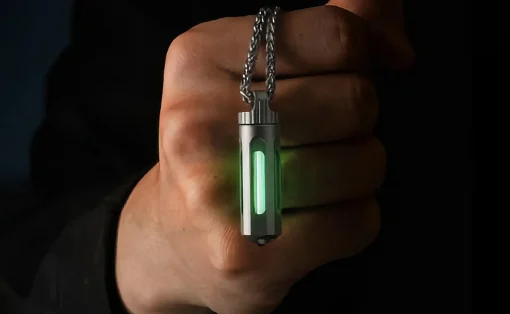 Metal rectangular pendant with a vertical green glow, hanging from a silver chain and held by a hand.