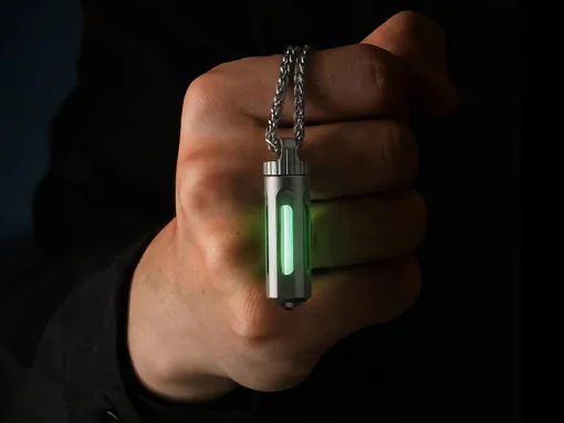 Metal rectangular pendant with a vertical green glow, hanging from a silver chain and held by a hand.