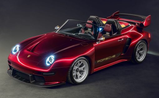 Red Porsche convertible sports car with open top, sleek headlights, and a large rear wing in a studio setting with a dark backdrop.