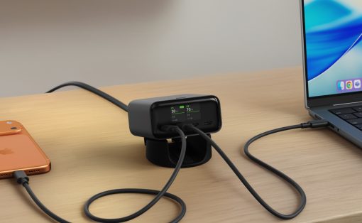 Black USB-C hub dock on a wooden desk connected to a laptop and an orange iPhone via charging cables