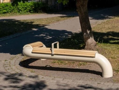 Curved white pipe bench with wooden slats beside a tree in a park setting
