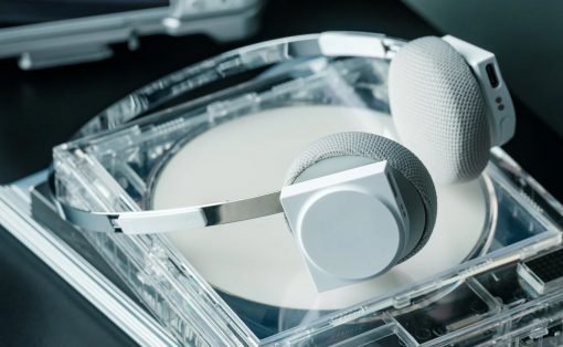 Over-ear white and gray headphones resting on an open transparent CD case with a disc inside.