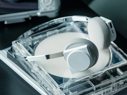 Over-ear white and gray headphones resting on an open transparent CD case with a disc inside.