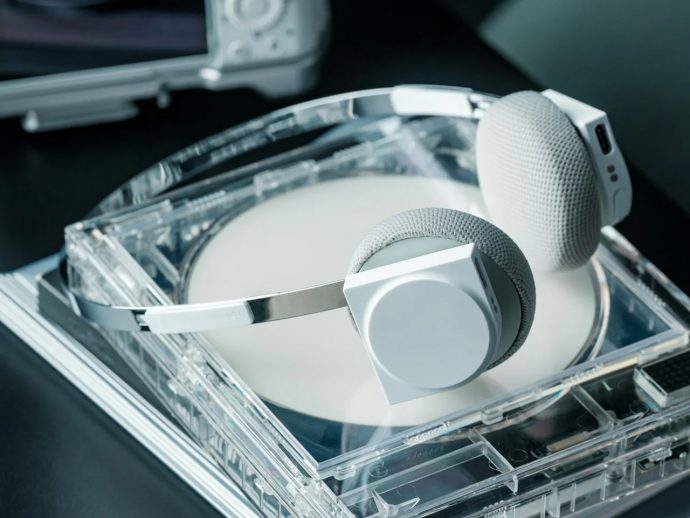 Over-ear white and gray headphones resting on an open transparent CD case with a disc inside.