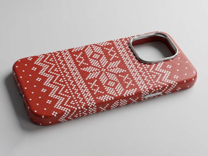 Red phone case with a white knitted Nordic pattern and a circular metal camera cutout, laid on a light gray surface.