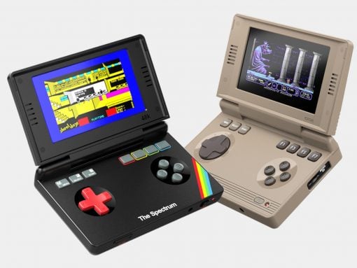 Two vintage handheld game consoles from the 1980s: a black Spectrum-style device with a red D-pad and rainbow stripe, and a beige handheld with a screen and multiple buttons on the side.