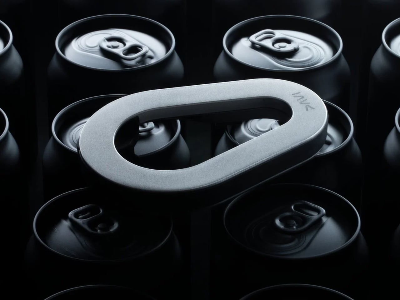 Silver oval metal loop resting across the tops of stacked dark beverage cans in a moody lighting setup