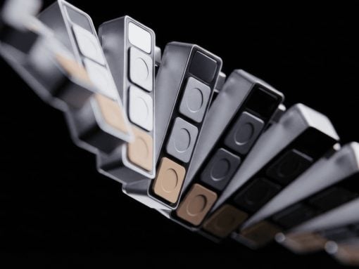 Close-up of a curved fan of color swatches in grayscale and warm beige tones against a black background.