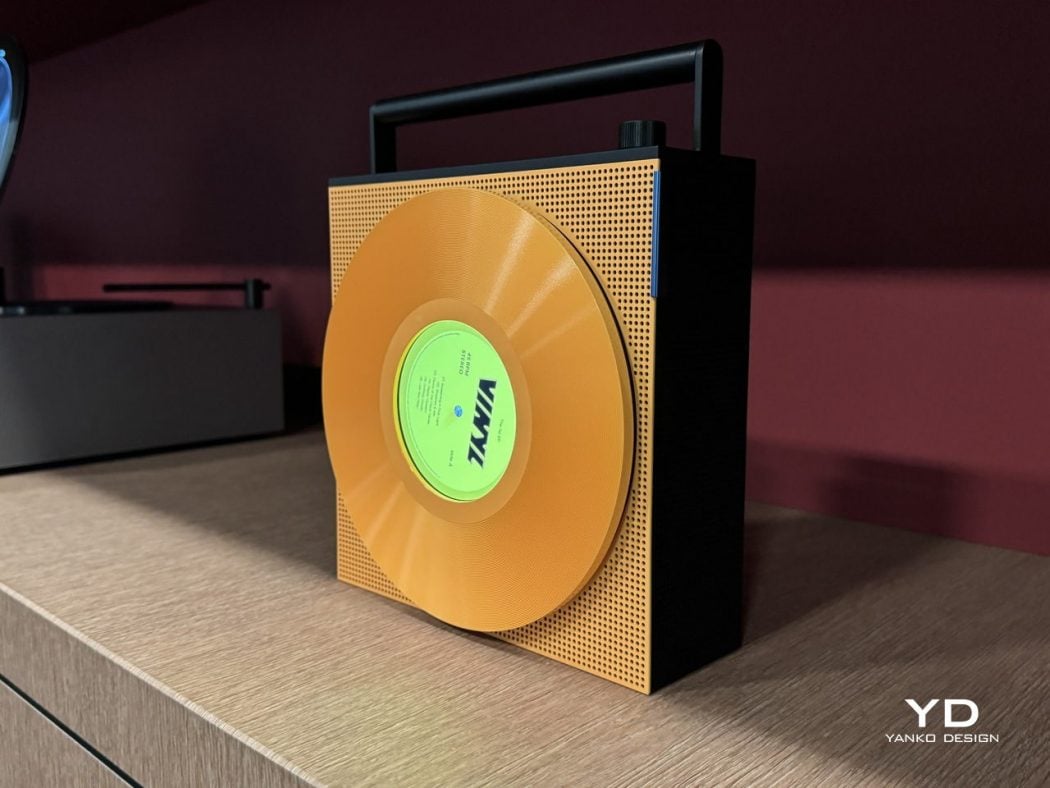 Gold vinyl record mounted on a perforated orange panel with a black base, posed on a wooden cabinet as a design sculpture.