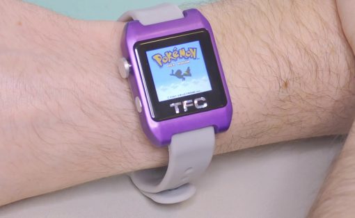 Purple toy smartwatch on a wrist displaying a Pokémon game screen at center of the display.