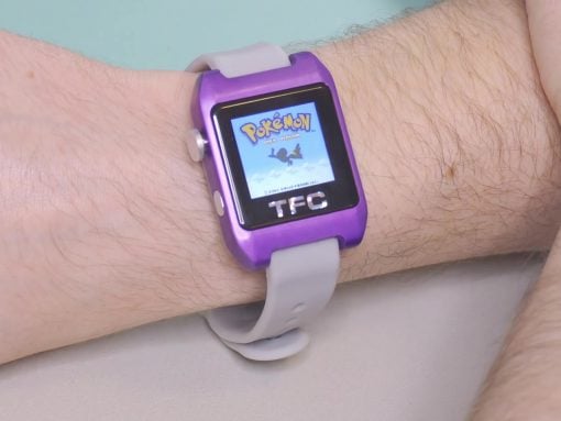 Purple toy smartwatch on a wrist displaying a Pokémon game screen at center of the display.
