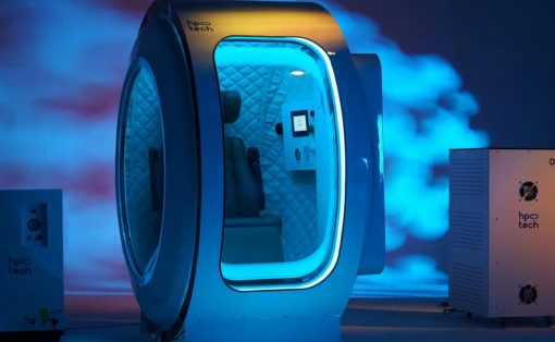 Futuristic blue-lit capsule pod with a glass door and quilted interior, branded 'hpc tech', connected to a control unit on the right.