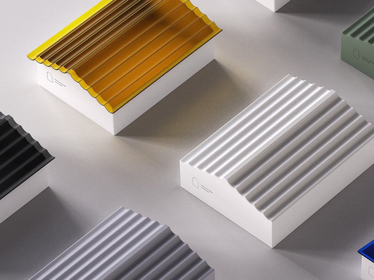 Row of white rectangular boxes with ribbed corrugated lids in yellow, black, gray, white, green, and blue on a pale surface.