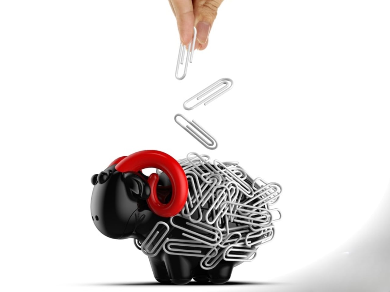 Piggy bank wrapped in silver paperclips with a hand dropping another paperclip, symbolizing saving being hindered by clutter or paperwork.