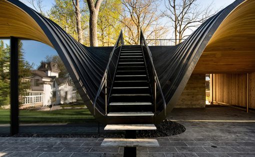 Dramatic black curved staircase inside a modern house, surrounded by curved metal shells and glass walls