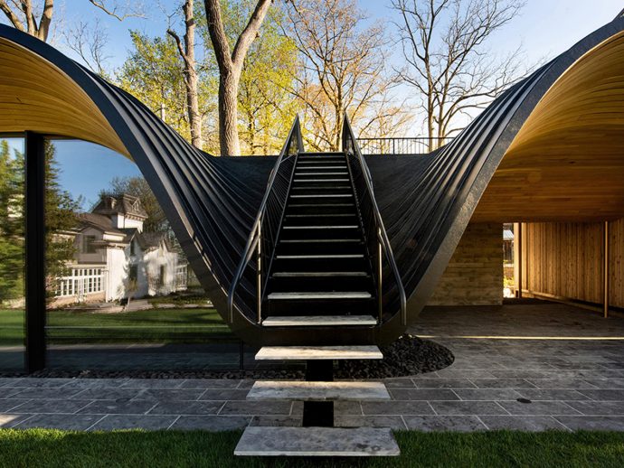 Dramatic black curved staircase inside a modern house, surrounded by curved metal shells and glass walls