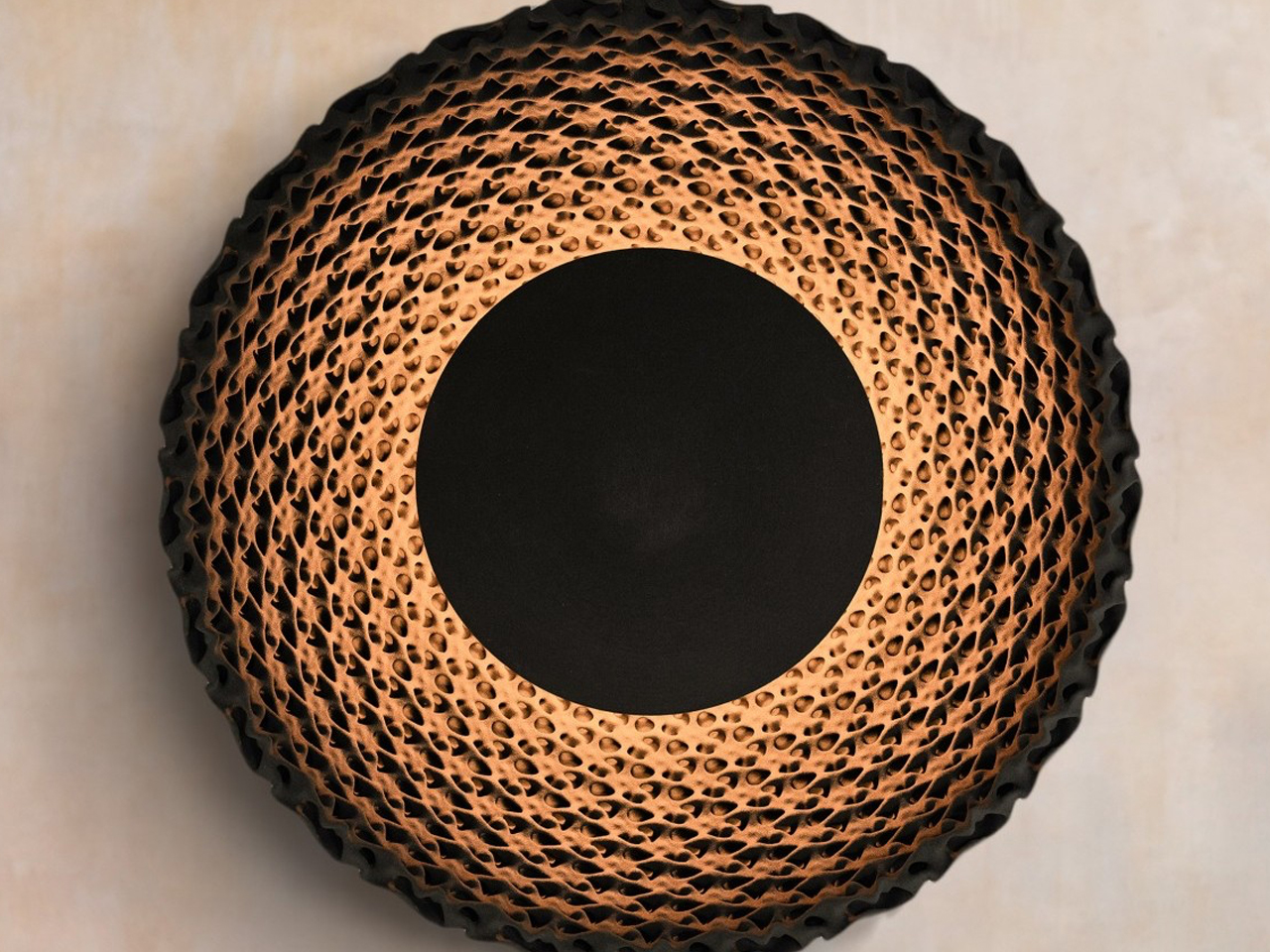 Circular pendant lamp with a honeycomb perforated shade emitting warm amber light.