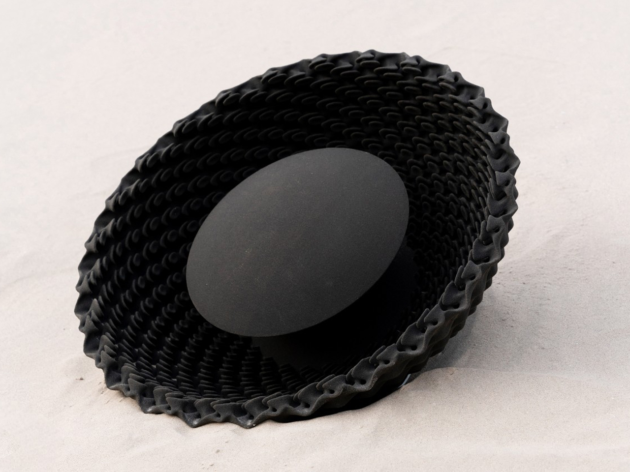 Decorative black woven bowl with a solid circular base resting on a light surface