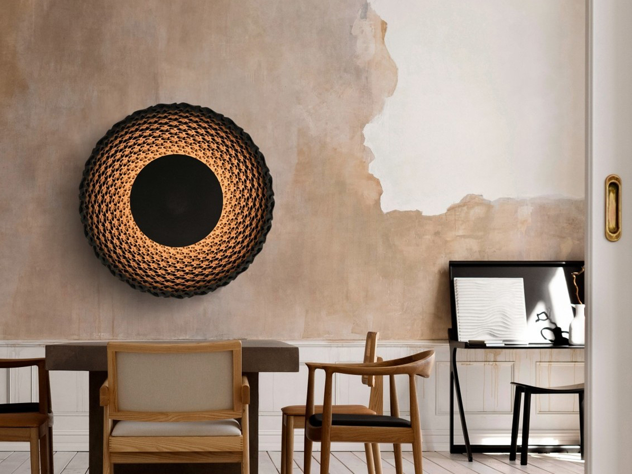 A modern dining area with a large woven circular wall light above a wooden table and chairs on a neutral wallative backdrop.