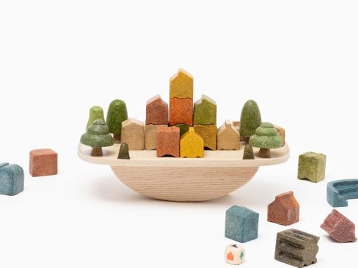 Wooden toy city: colorful houses and trees arranged on a round wooden tray, with extra blocks around it.