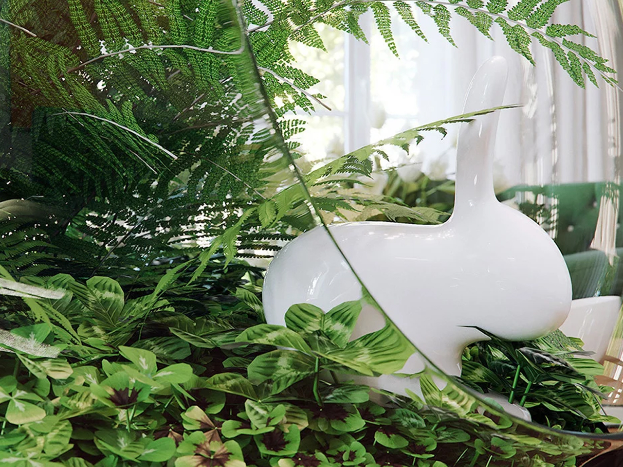 White swan sculpture nestled among lush green ferns and tropical plants in a bright indoor setting.