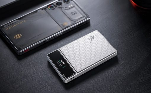 Two modern smartphones on a dark wooden desk, one with a textured white honeycomb back and a small display, the other with a clear protective case revealing its internals and camera array.