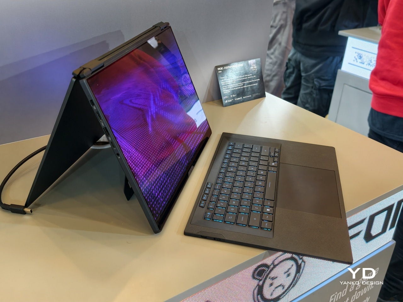 Two-in-one laptop set in tent mode on a display table, screen glowing purple.