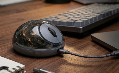 Spherical black JUMA USB microphone on a wooden desk, connected by a cable to a laptop with a notebook and pen nearby.