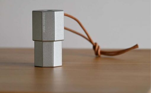 Two silver cube-shaped metal blocks stacked, tied with a brown leather cord on a wooden table surface.