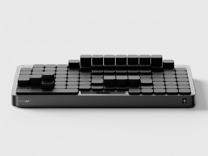Low-angle view of a black modular keyboard with raised square keys, branded 'MOSAIC' on the front edge.