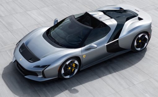 Top-down view of a silver Ferrari sports car on a gray tiled surface, highlighting its low, aerodynamic shape and open cockpit.