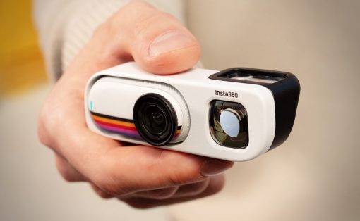 Person holding a white Insta360 action camera, lens facing forward in a hand